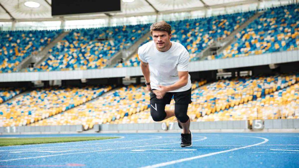 مردی در حال دویدن در مسیر مسابقه در استادیوم